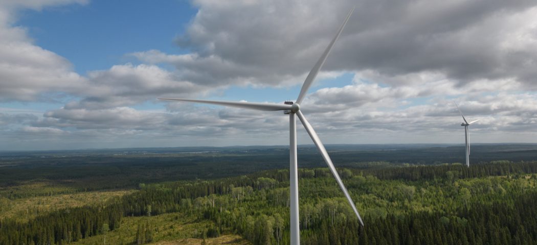 två vindkraftverk i skogsmiljö